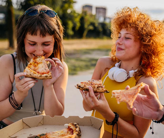 Two ladies eating pizza.