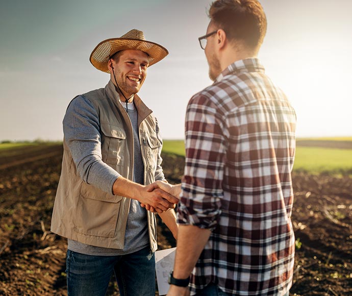 Two farmers shaking hands in the field.
